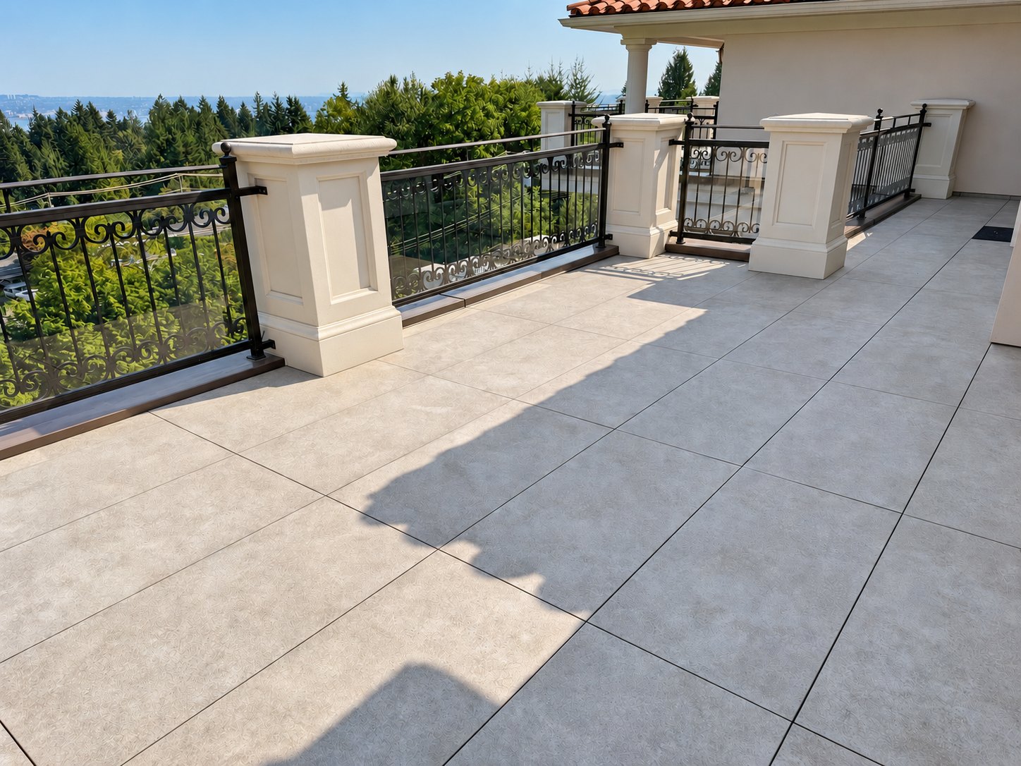 Renovated deck in West Vancouver with large-format pavers, white columns and black railings
