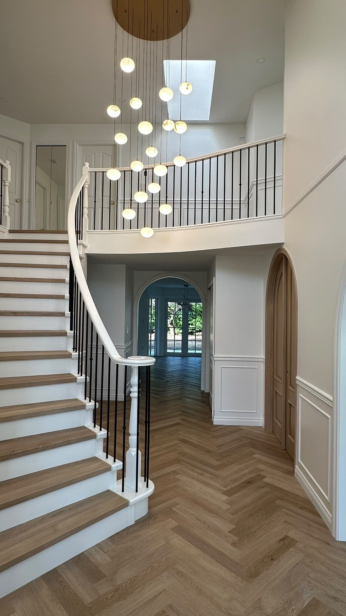 North Vancouver stair hall with a curved balustrade and cascading globe pendants