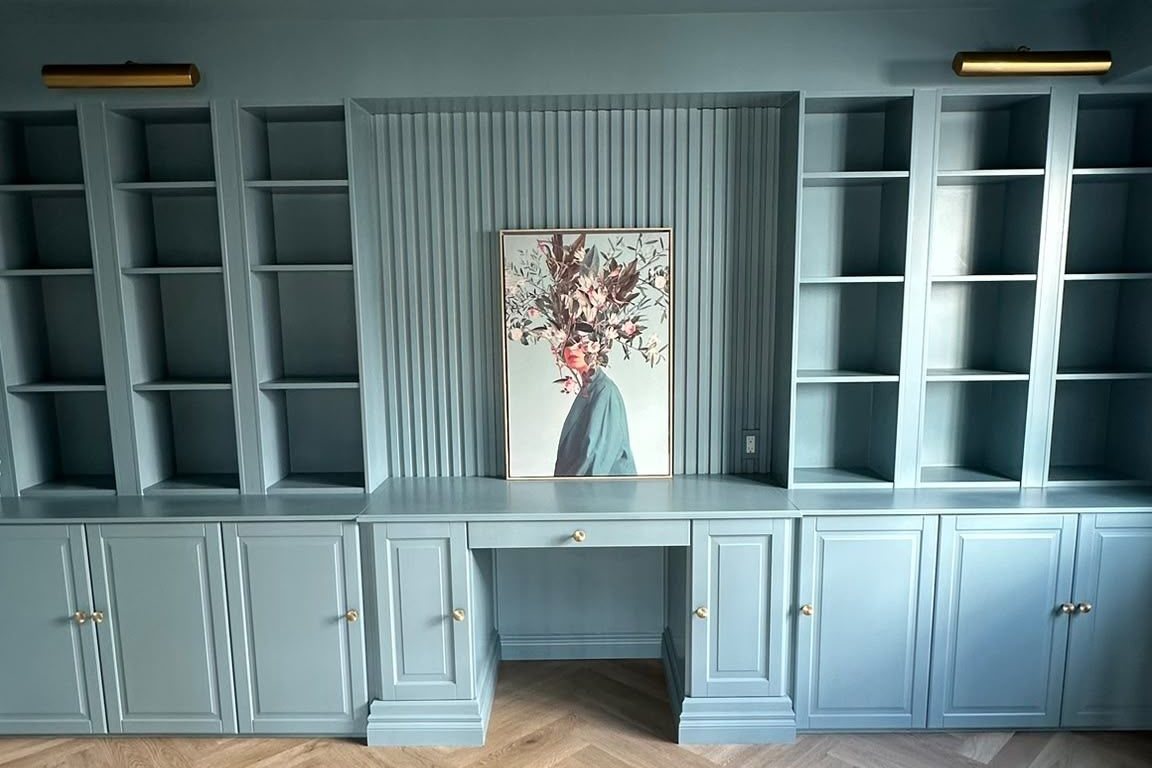 Blue painted office built-ins with shelving and a central desk nook