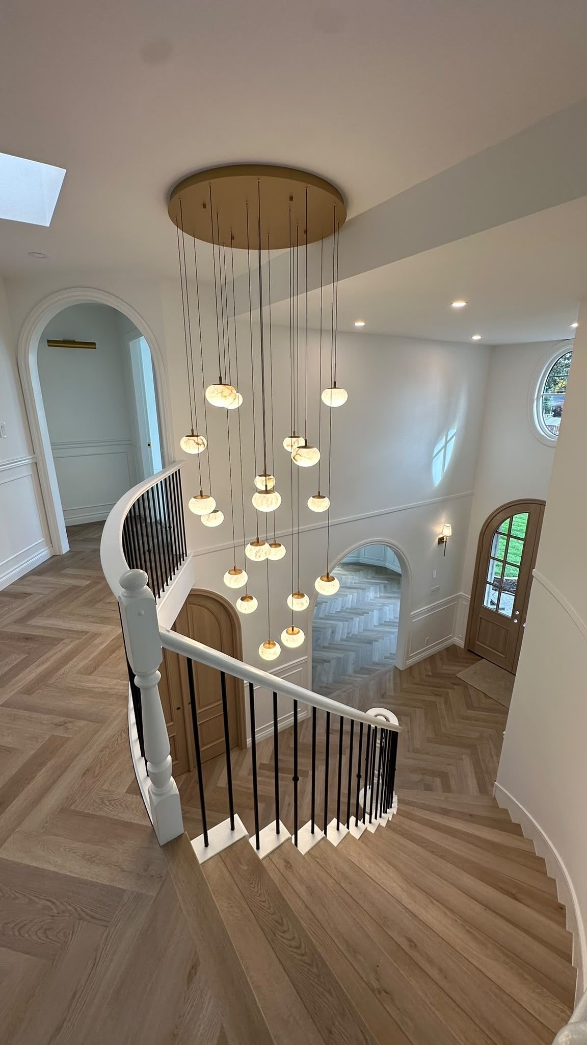Looking down through globe pendants into the curved stair hall