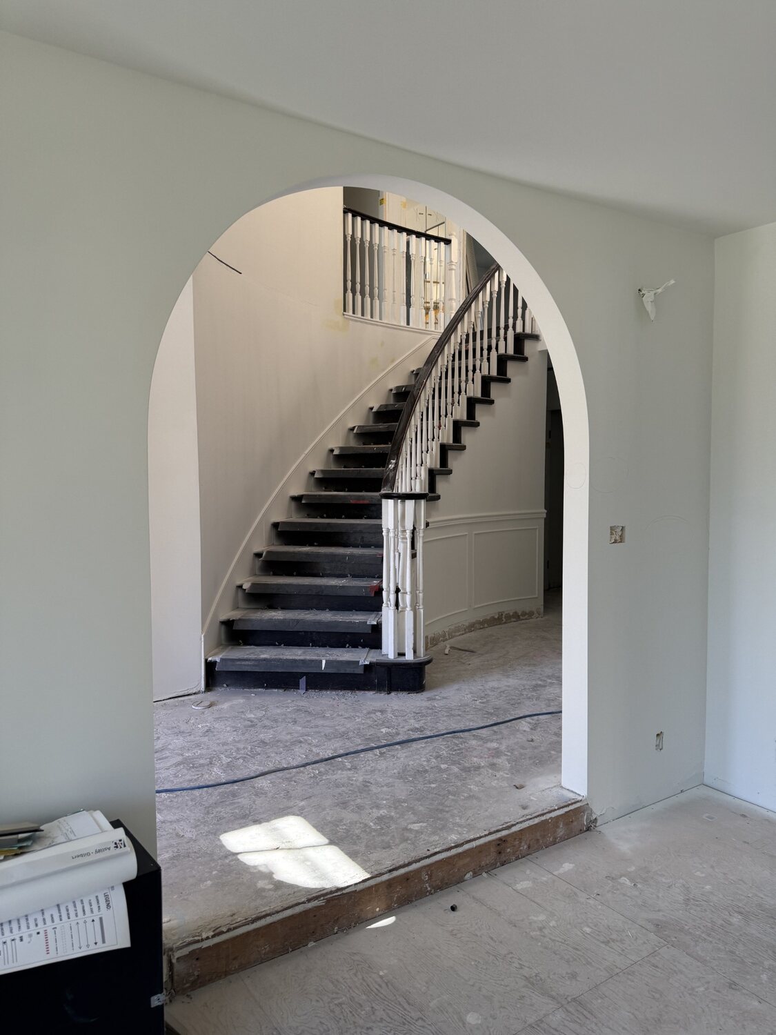 Plaster archway framing a curved staircase, Viney Road renovation in North Vancouver